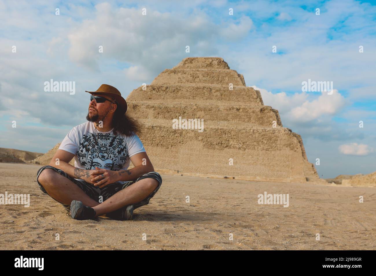 One Tourist Posing with the Step Pyramid of Djoser on the background in the Saqqara necropolis archaeological site, northwest of the city of Memphis Stock Photo
