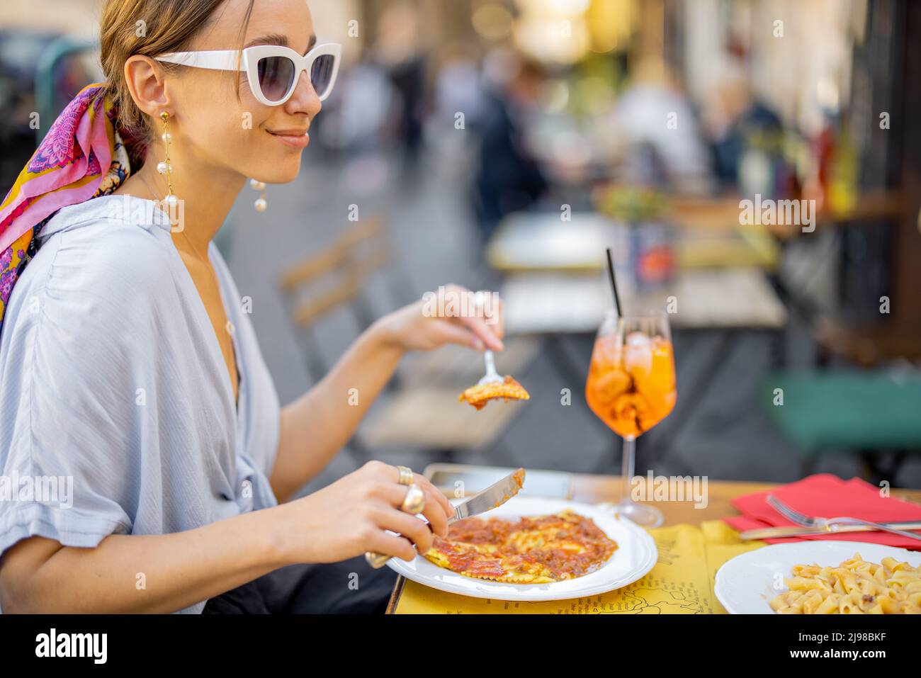 Woman eating italian pasta at restaurant on the street in Rome Stock Photo