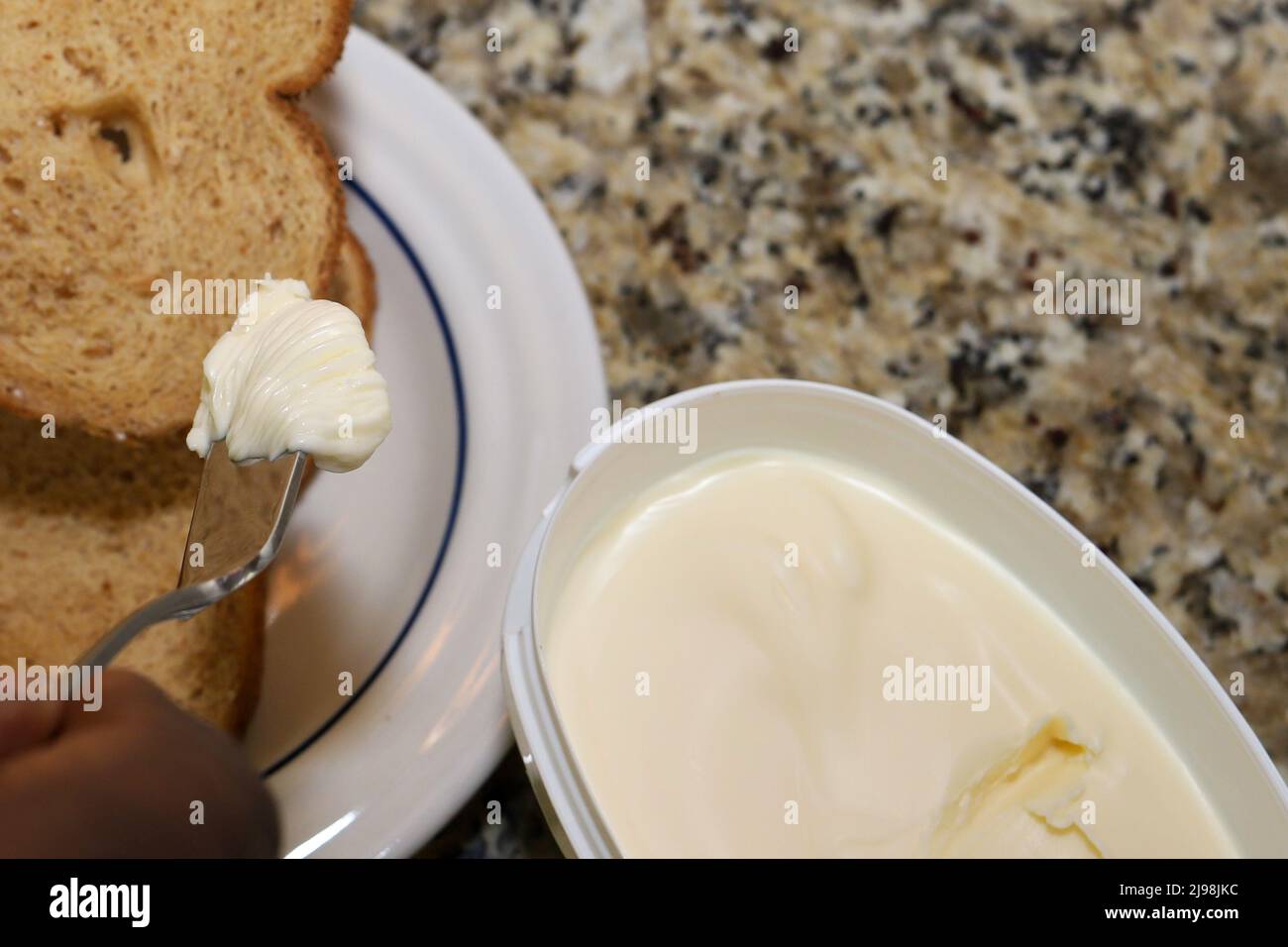 Close-up of a man spreading organic butter on whole wheat bread Stock Photo