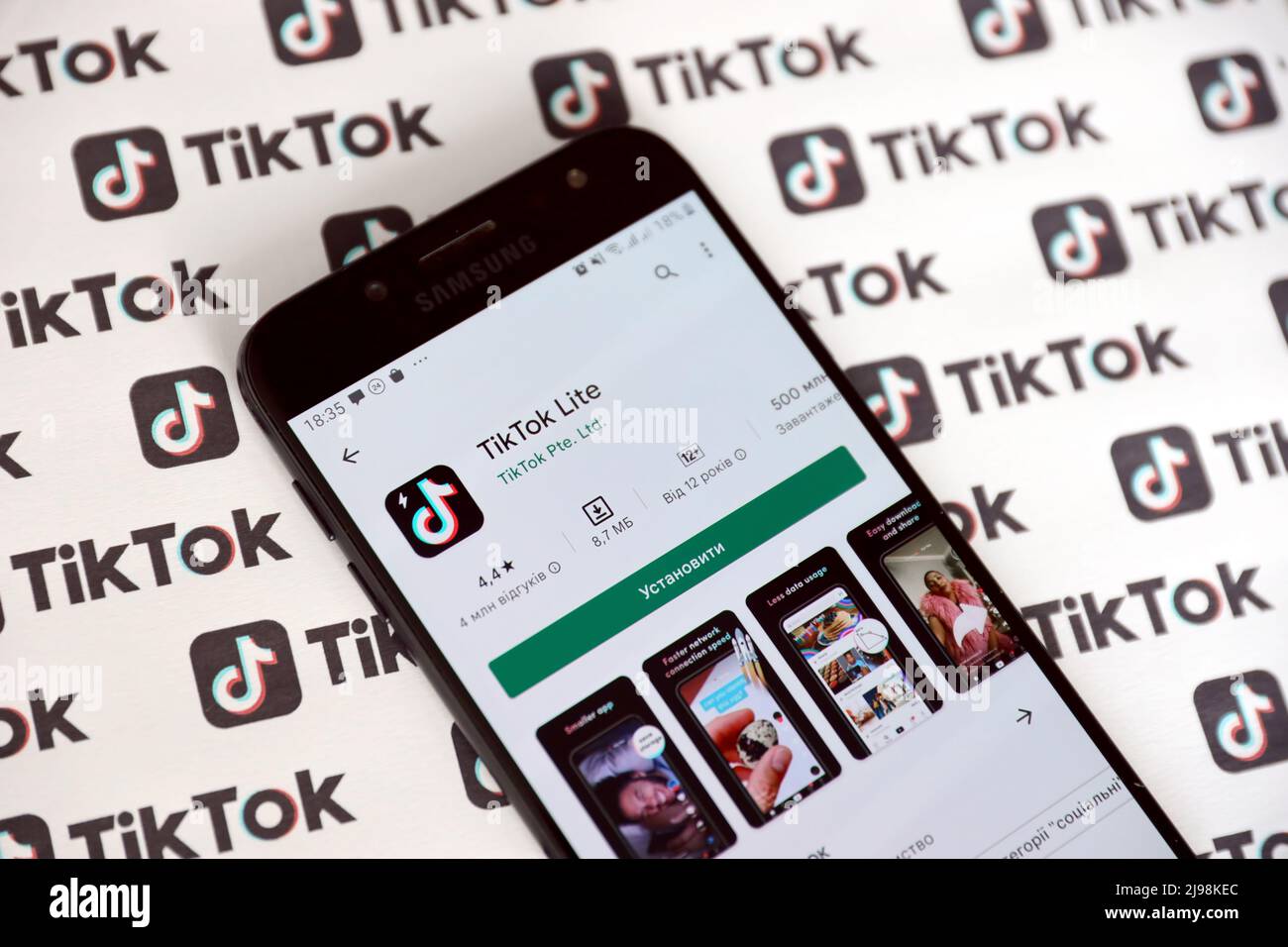 TERNOPIL, UKRAINE - MAY 2, 2022: Tik Tok smartphone app on screen and Many TikTok logo printed on paper. Tiktok or Douyin is a famous Chinese short-fo Stock Photo