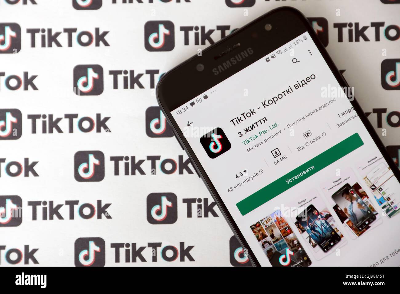 TERNOPIL, UKRAINE - MAY 2, 2022: Tik Tok smartphone app on screen and Many TikTok logo printed on paper. Tiktok or Douyin is a famous Chinese short-fo Stock Photo