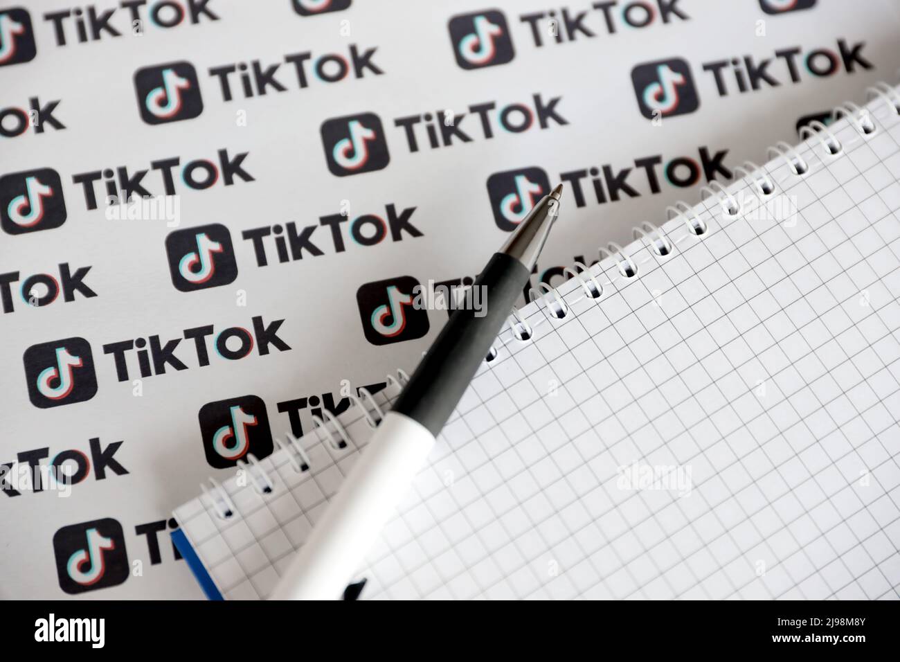TERNOPIL, UKRAINE - MAY 2, 2022: Notepad with pen and Many TikTok logo printed on paper. Tiktok or Douyin is a famous Chinese short-form video hosting Stock Photo