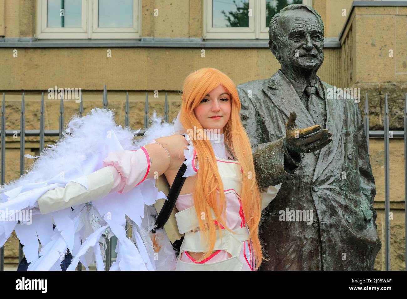 Düsseldorf, NRW, Germany, 21st May 2022. A young woman in cosplay outfit poses with the statue of former premier of NRW, Johannes Rau. Tens of thousands of visitors and cosplayers enjoy the warm sunshine along the river Rhine embankment in their outfits inspired by Japanese anime, video and games. Stage performances, cosplay, stalls and demonstrations of Japanese culture, sports and traditions are featured at Düsseldorf's annual Japan Day, celebrating Japan and the Japanese community in the city. Düsseldorf is home to the largest Japanese community in Germany. Stock Photo