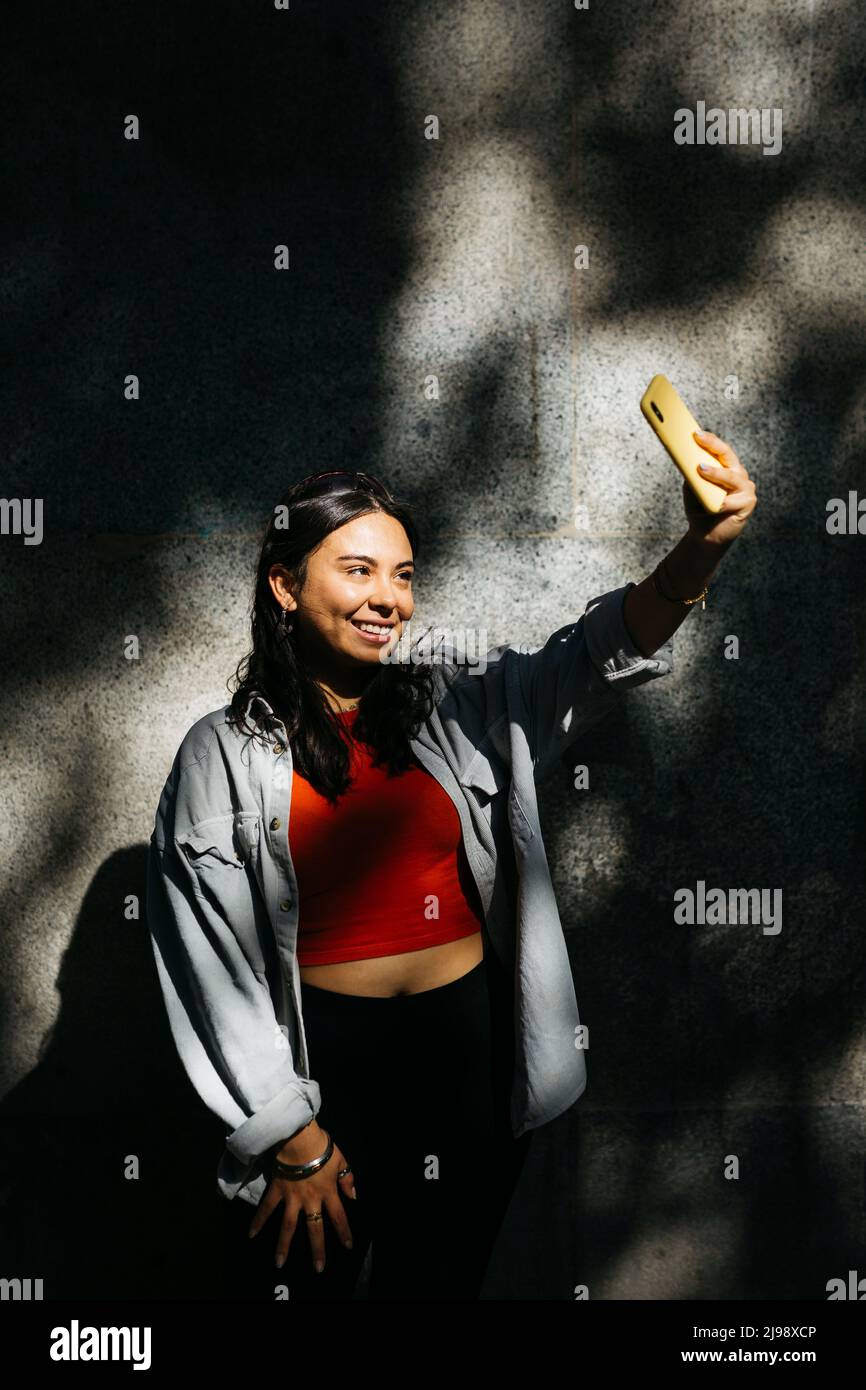 Portrait of a young woman taking a selfie with a yellow phone Stock ...