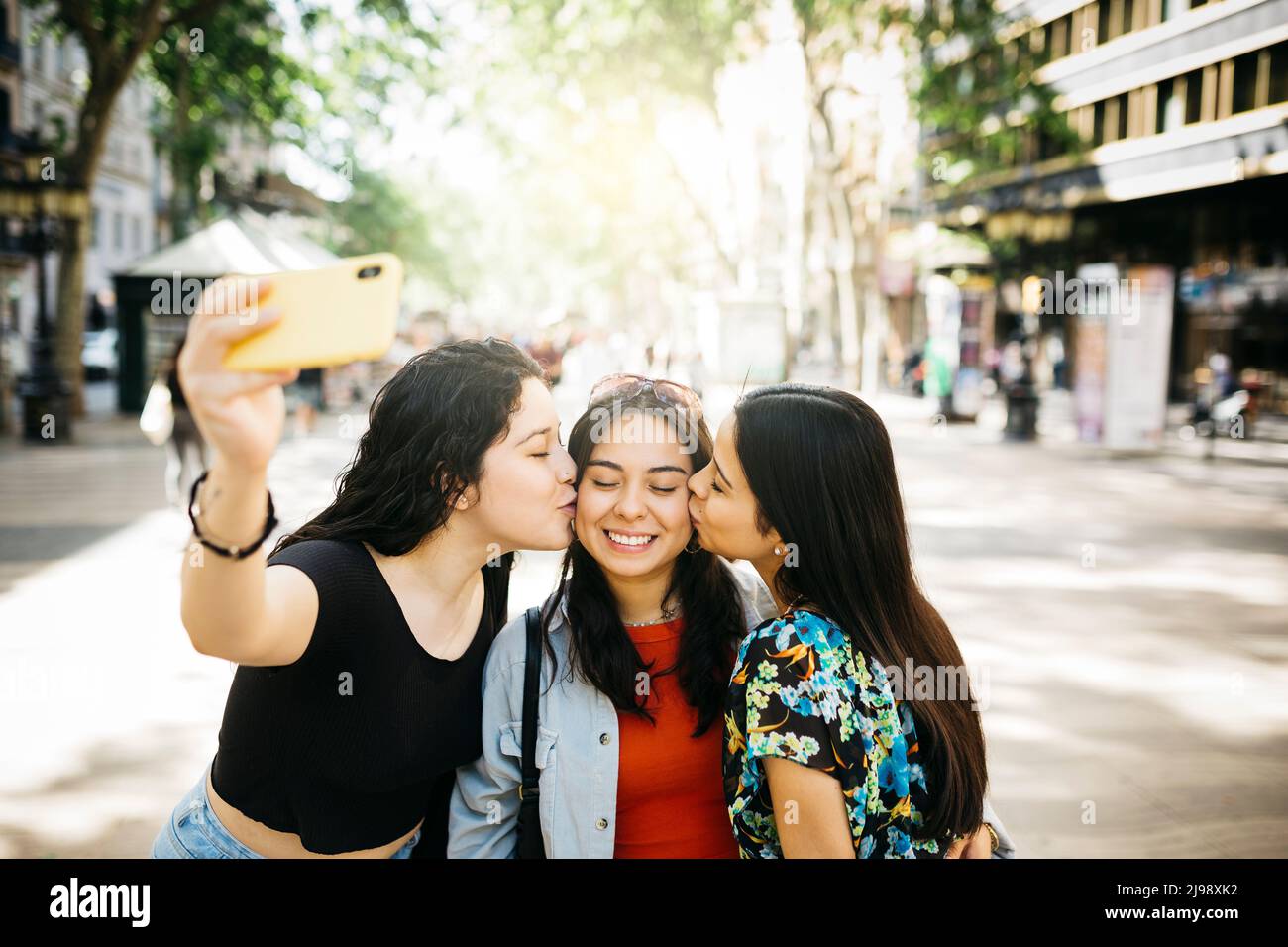 Three young women walking down Las Ramblas of Barcelona and taking a selfie, while kissing, with a phone Stock Photo