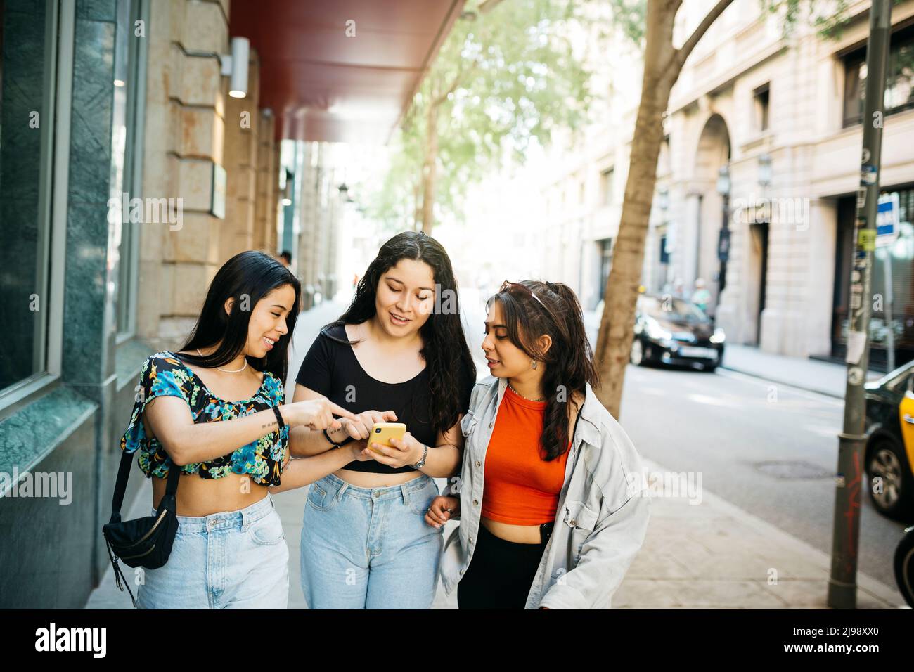 Three young women walking and hanging out on a comercial street of a big city Stock Photo