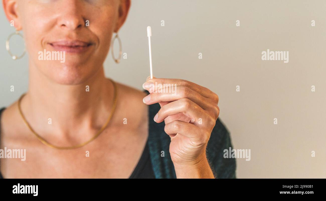 CLose shot of Woman holding covid 19 PCR test swab clean background Stock Photo