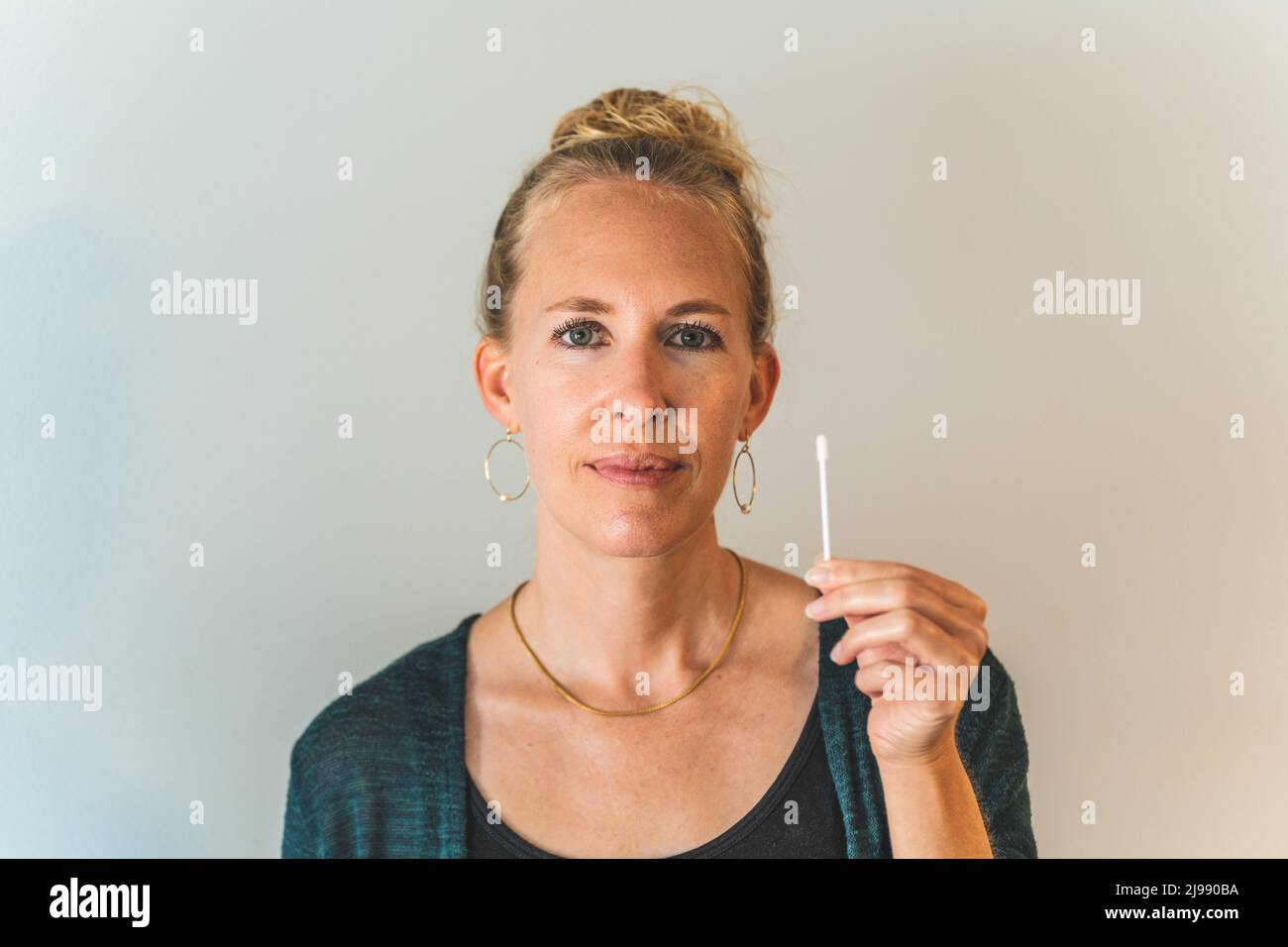 blonde Woman holding covid 19 PCR test swab clean background Stock Photo