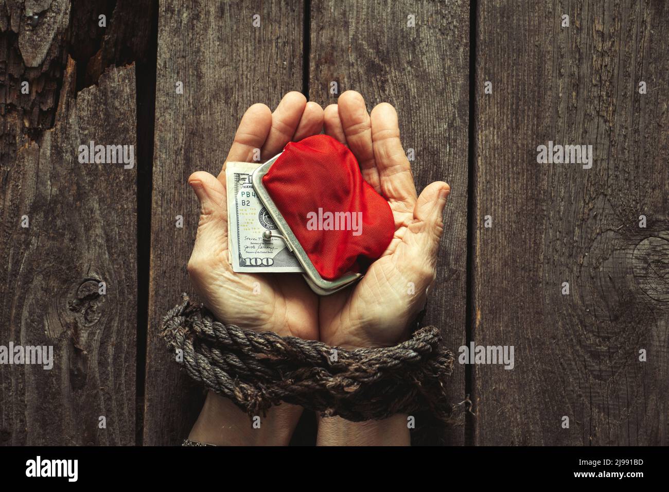 red wallet with American dollars in the girl's tied hands on the table Stock Photo