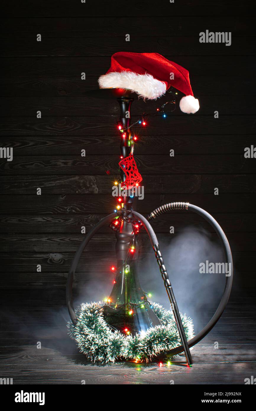 christmas hookah with glowing garland and christmas red hat on dark background Stock Photo
