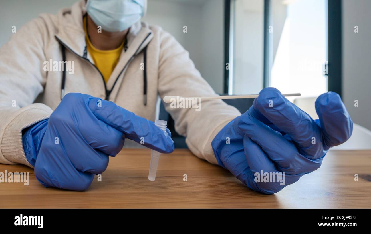 Man wearing mask and latex gloves taking a self swabbing home tests for