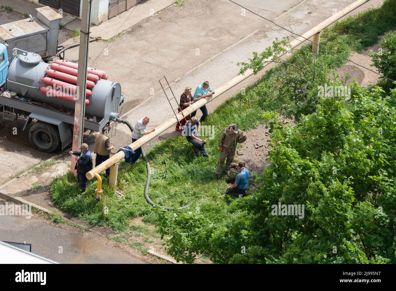 Tiraspol, Moldova - May 17, 2022: Male workers fixes a break in a water supply and sewerage pipe. Accident on the line of urban infrastructure. Poor q Stock Photo