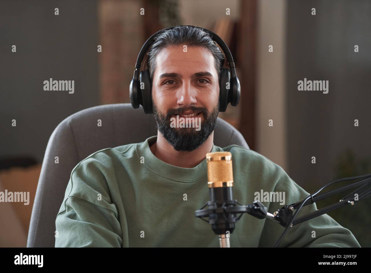 Medium close-up portrait of young Middle Eastern influencer wearing headphones creating content for blog looking at camera Stock Photo