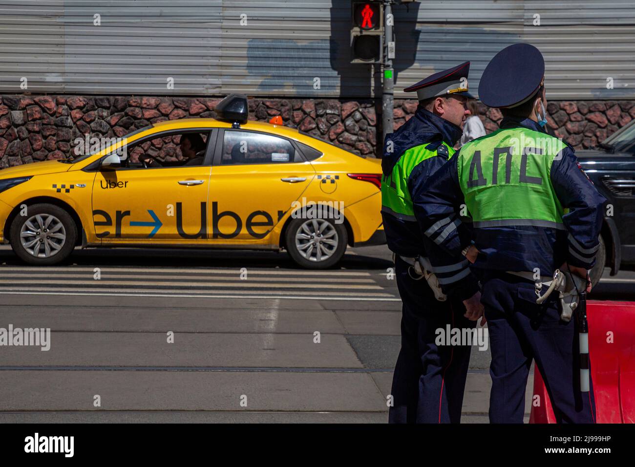 Moscow, Russia. 21st May, 2022. An Uber taxi rides down a street in the center of Moscow against a background of two traffic police officers, Russia Stock Photo