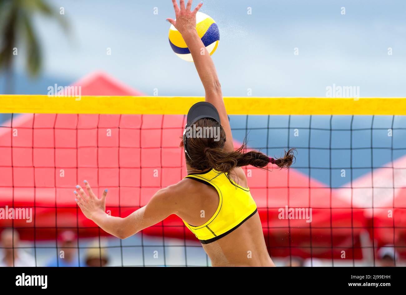A Beach Volleyball Player Is Jumping At the Net And Spiking The Ball