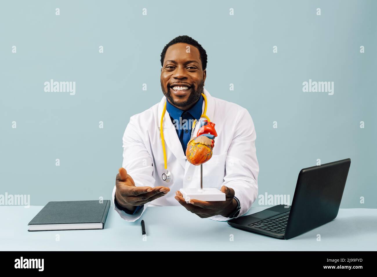 Black doctor with hearth model and a stethoscope isolated on pink background studio Stock Photo