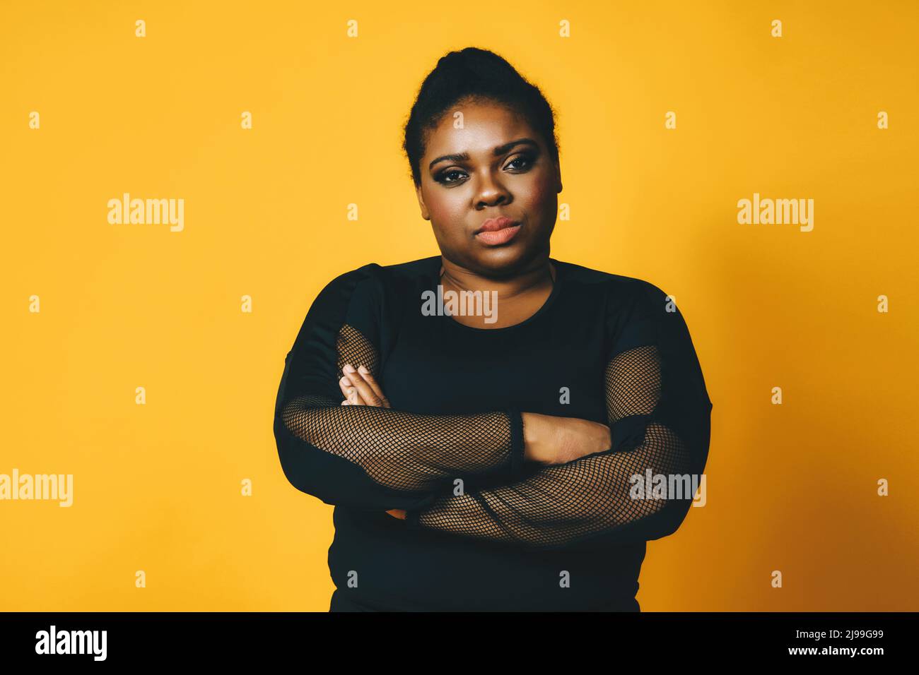 portrait of a beautiful black woman with crossed arms on yellow ...