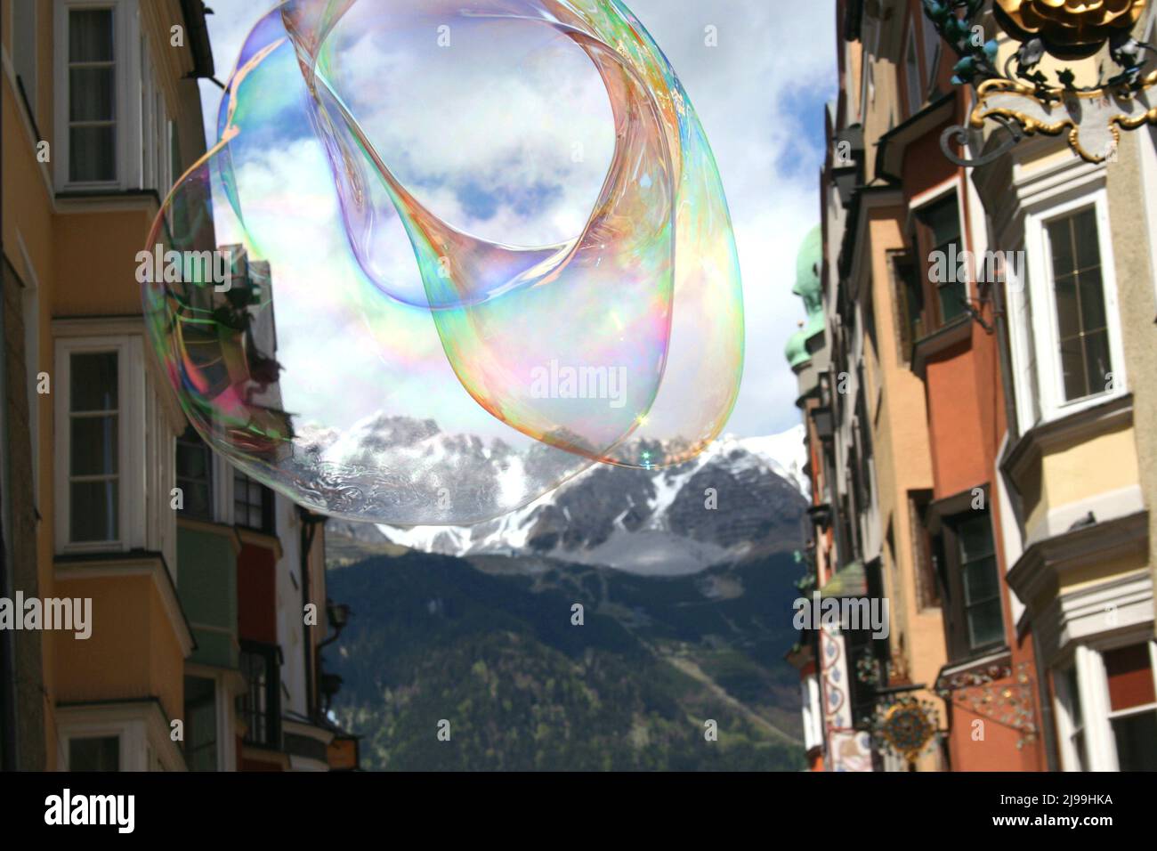 A large soap bubble with rainbow colors floats in the sky, framed by old buildings in Innsbruck. Stock Photo