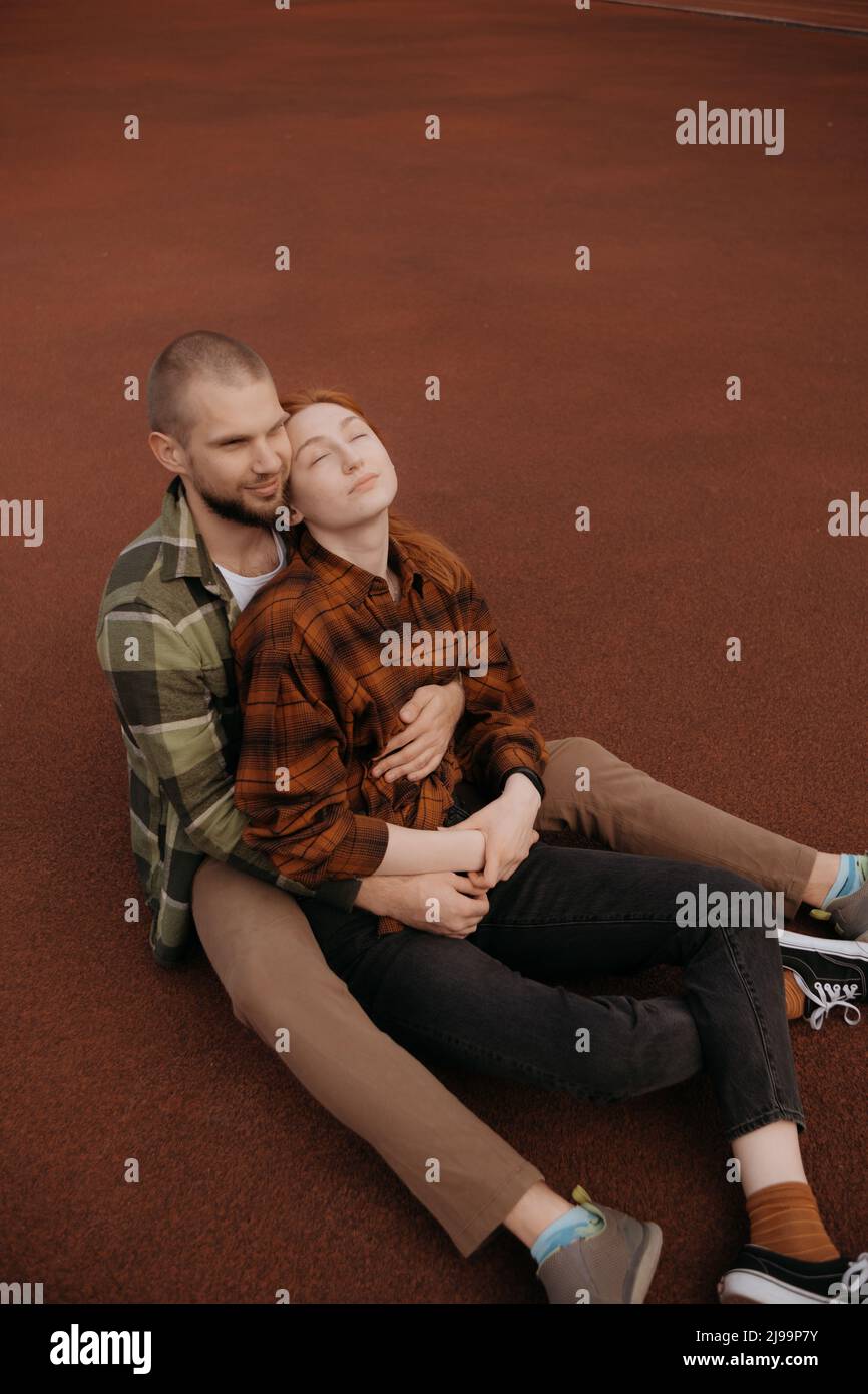 lovers sit in a hug on a red coating Stock Photo - Alamy