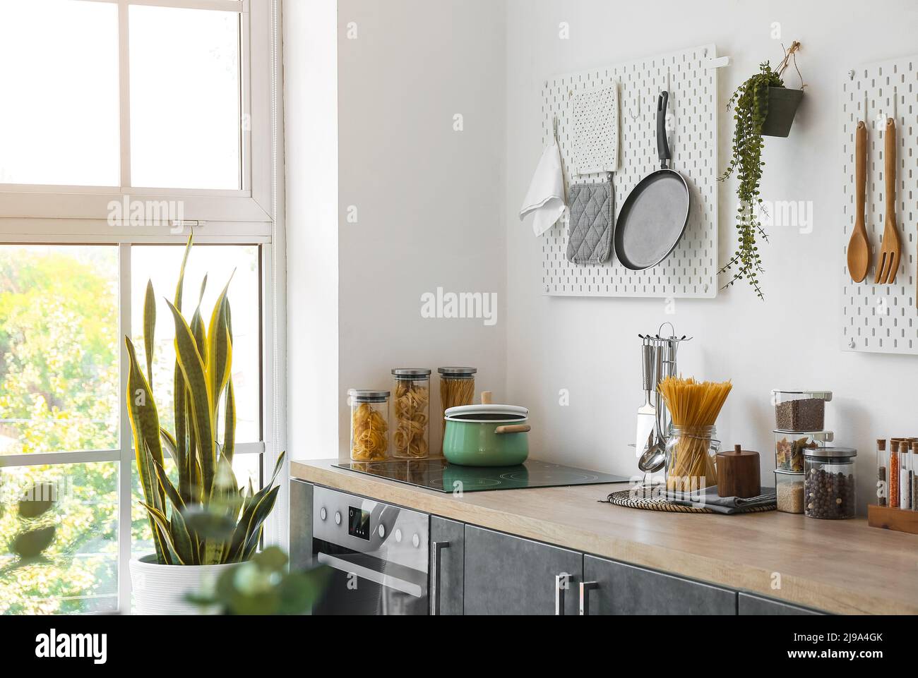 Stylish counters with utensils and pegboards on light wall in kitchen Stock Photo