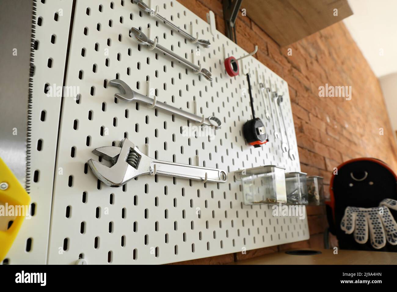 Pegboards with tools on brick wall in workshop Stock Photo
