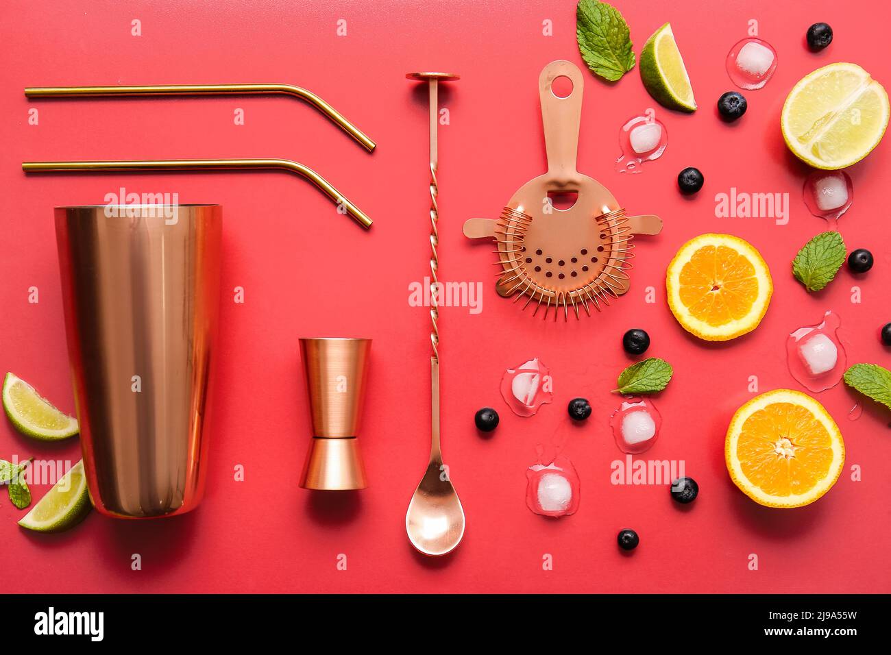 Different utensils and cocktail ingredients on red background Stock
