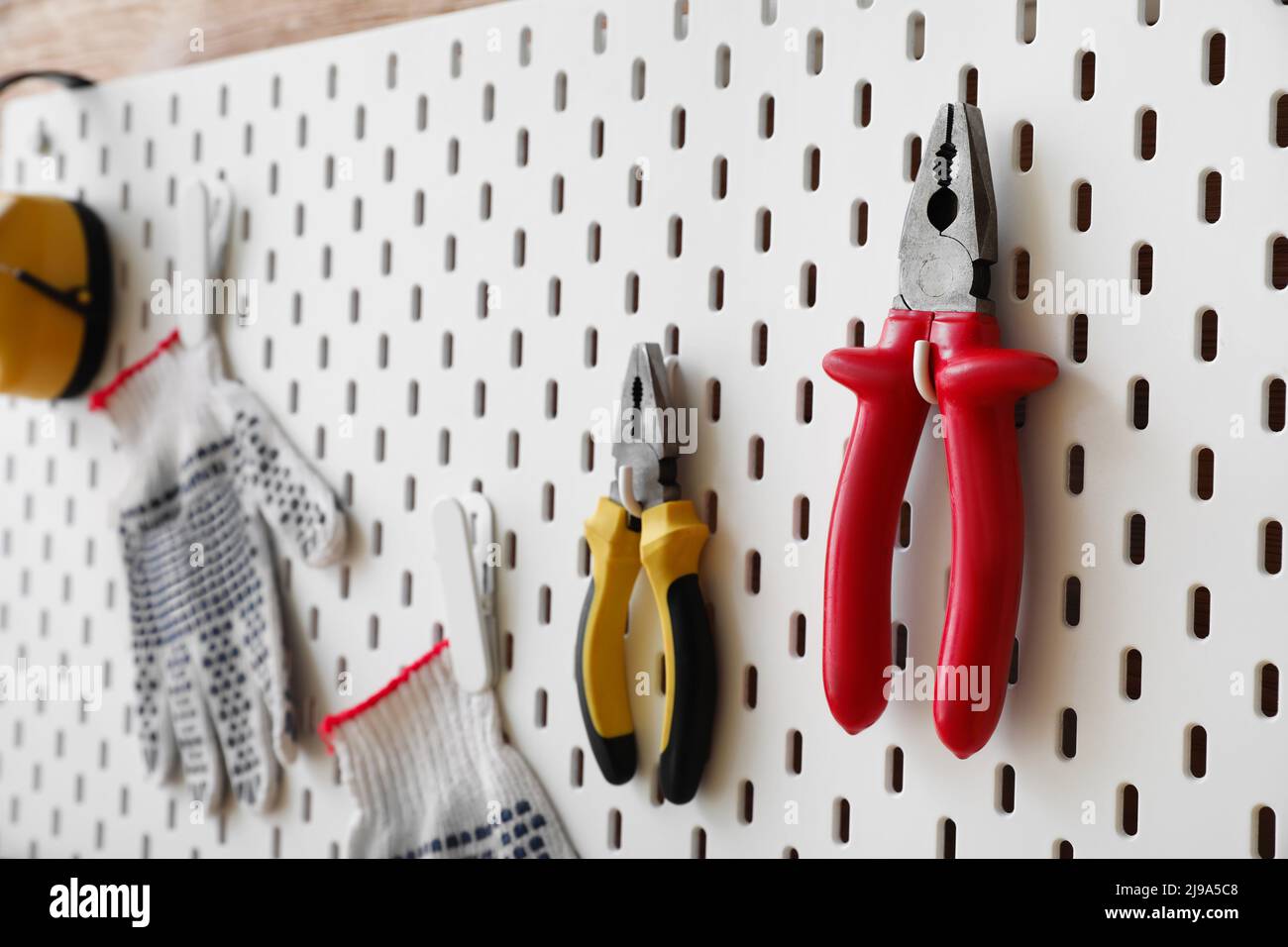 Pegboard with pliers and gloves, closeup Stock Photo Alamy