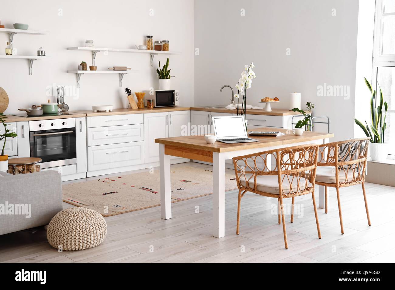 Modern interior of light kitchen with laptop on dining table Stock ...