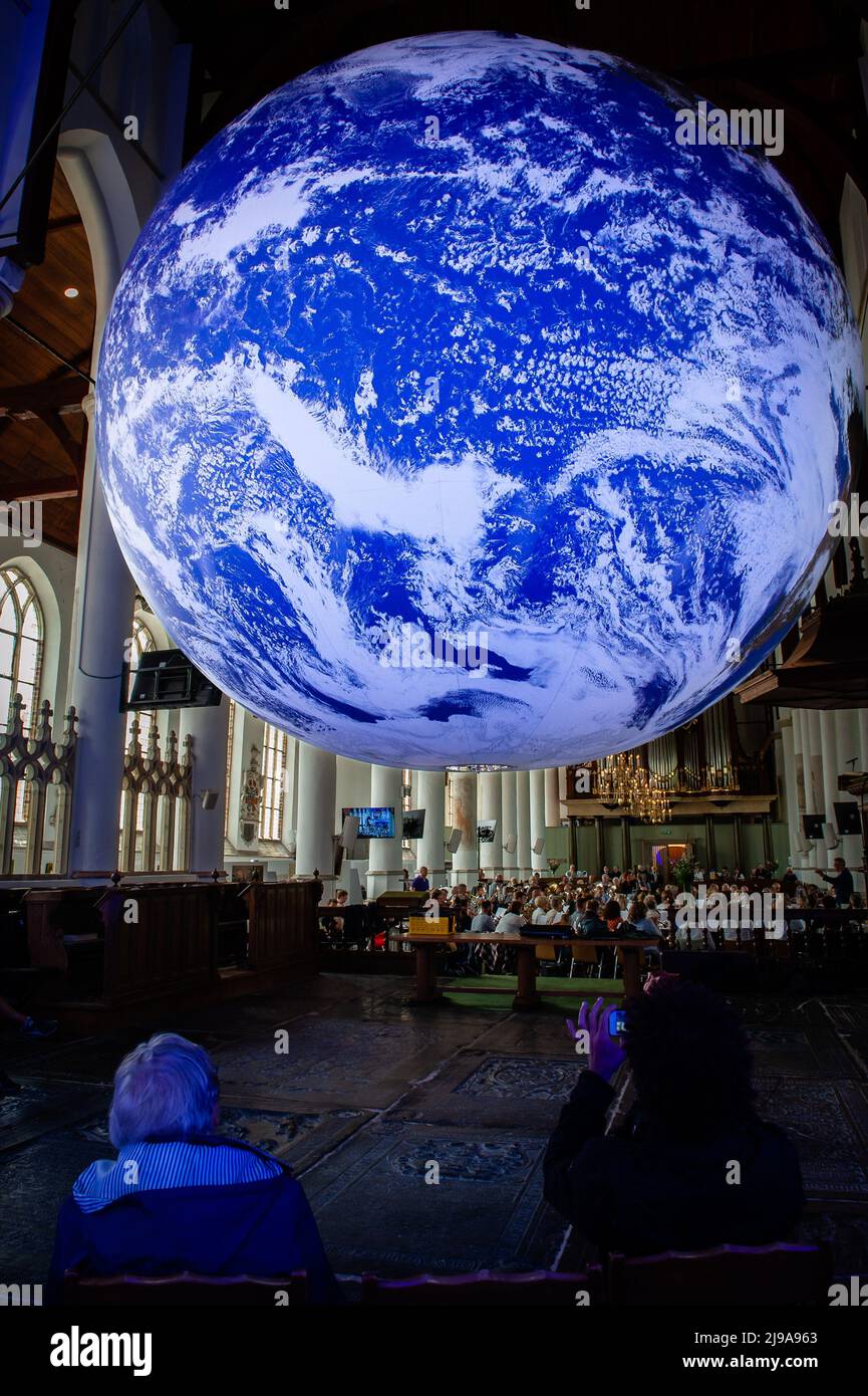 People are seen taking photos of the big Earth ball placed inside the church. Gaia is a touring artwork by UK artist Luke Jerram. Measuring seven meters in diameter and created from 120dpi detailed NASA imagery of the Earth surface, the artwork provides the opportunity to see our planet, floating in three dimensions. This experience gives people a sense of awe, a deep realization of the interconnectedness of life on Earth. In Greek mythology, Gaia is the personification of Mother Earth. This artwork belongs to Arcadia, a 100-day cultural program that is taking place this summer in the province Stock Photo