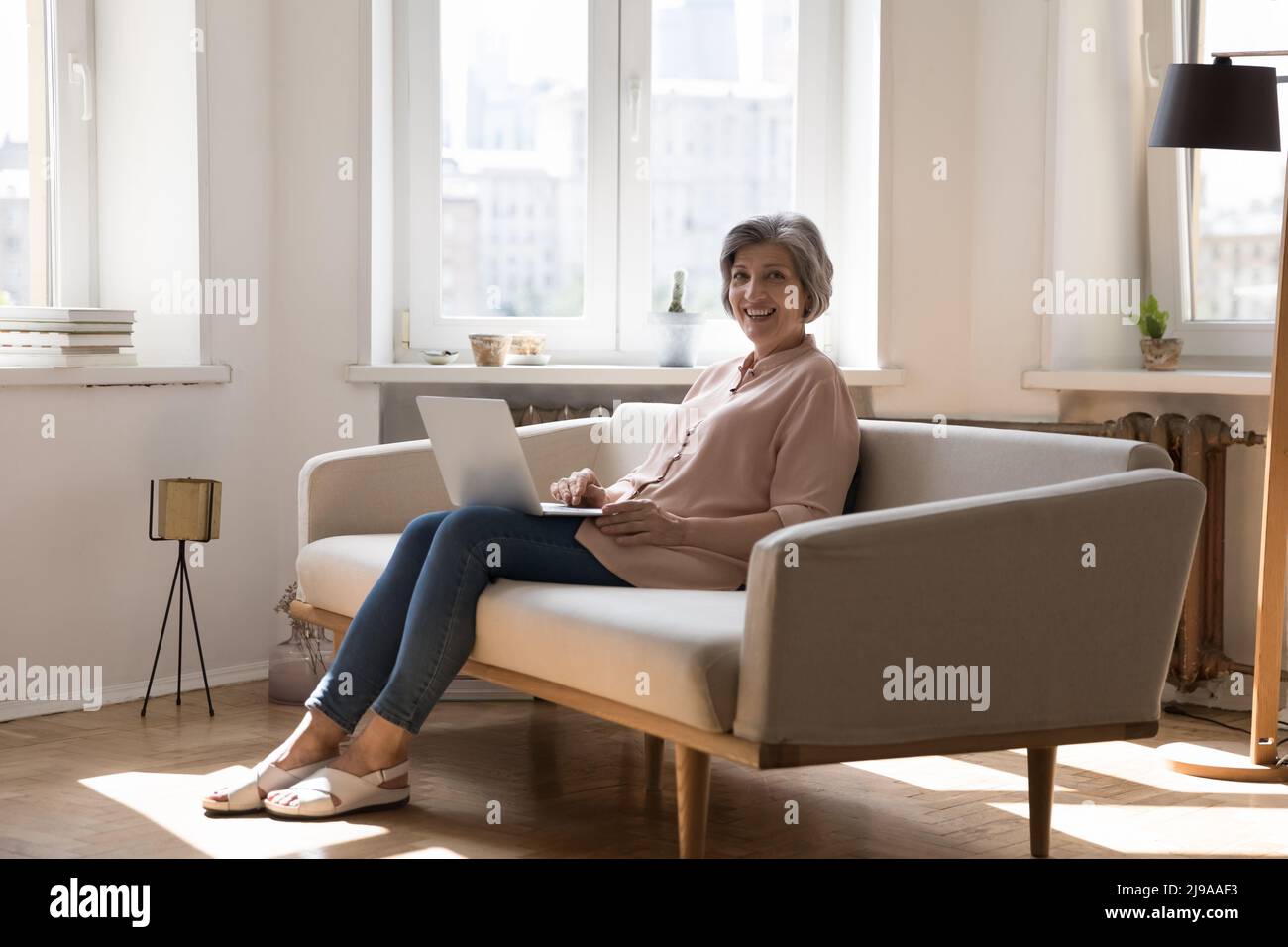 Cheerful happy mature freelancer lady using laptop Stock Photo