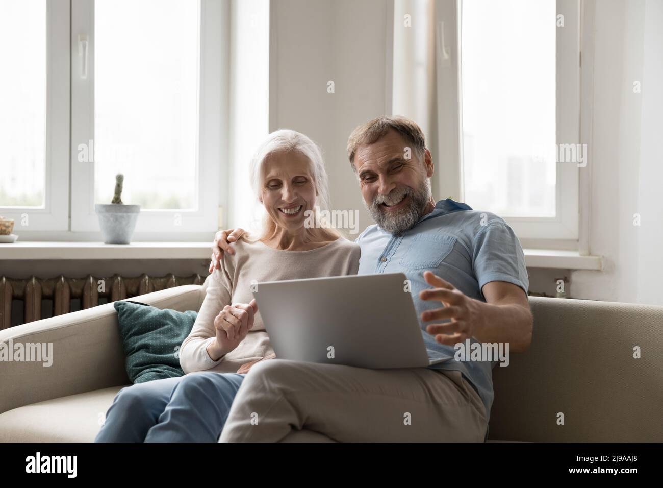 Happy excited mature couple using laptop at home Stock Photo