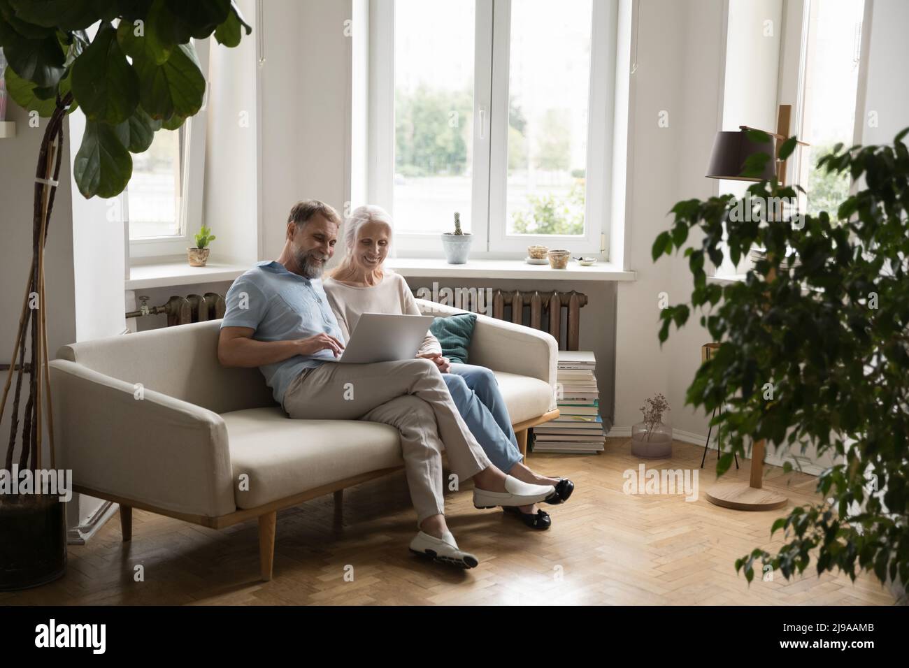 Cheerful married couple using online app on laptop computer Stock Photo