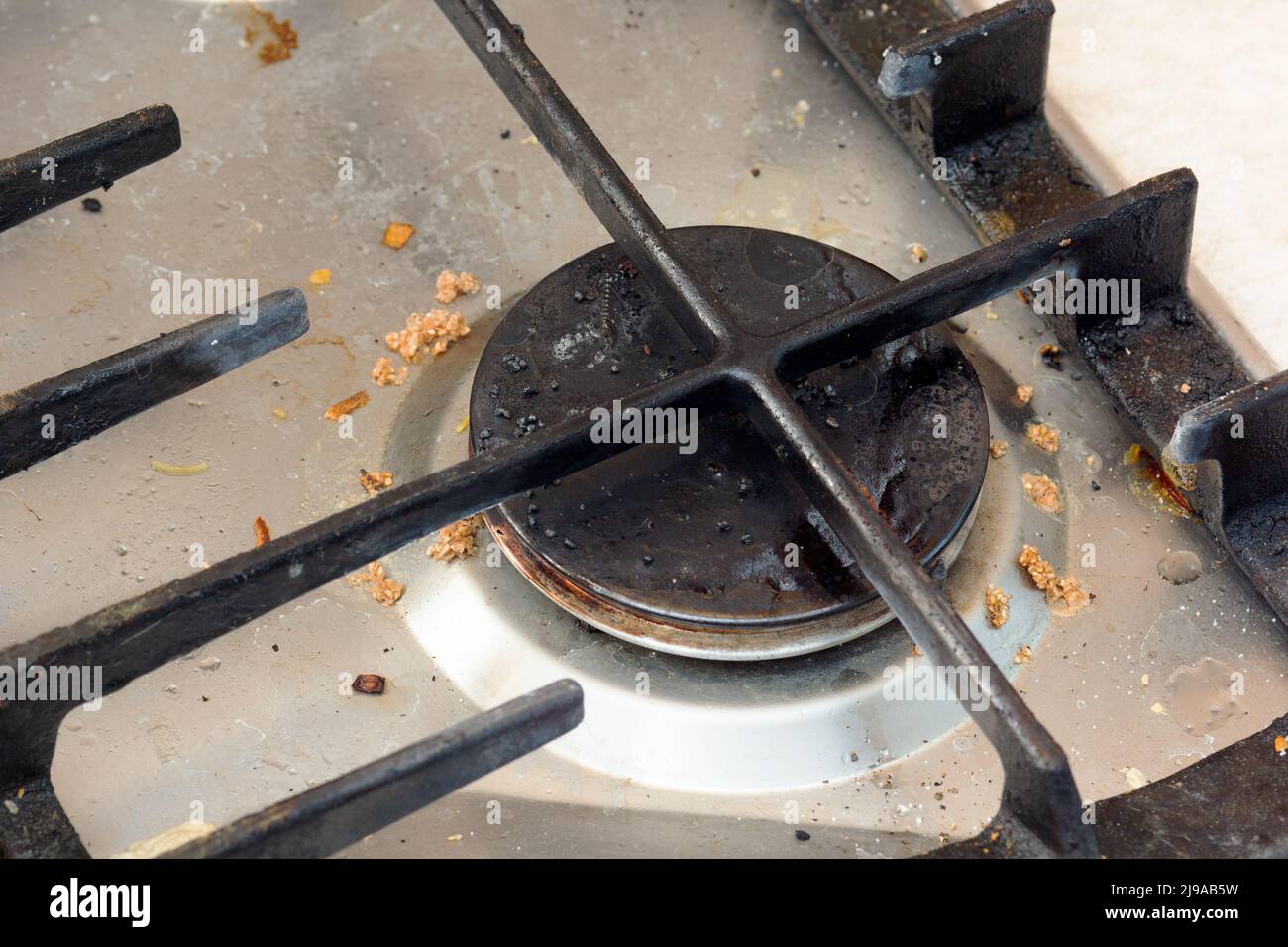 Dirty metallic surface of gas stovetop with burner cap and grate Stock
