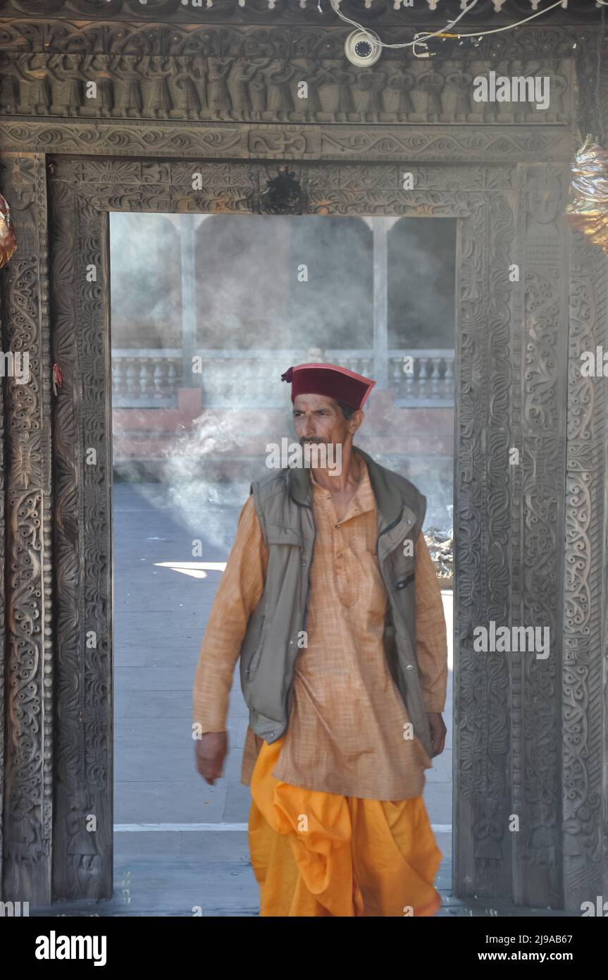 Mandi, Himachal Pradesh, India - 10 16 2021: Front view of a pujari (priest) wearing himachali topi (cap) and dhoti, looking sideways while walking out through temple door Stock Photo