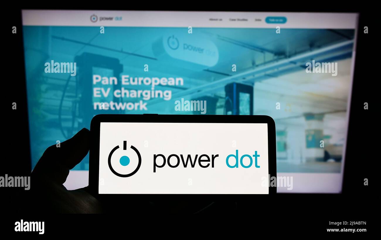 Person holding cellphone with logo of Portuguese EV charging company Power Dot SA on screen in front of business webpage. Focus on phone display. Stock Photo