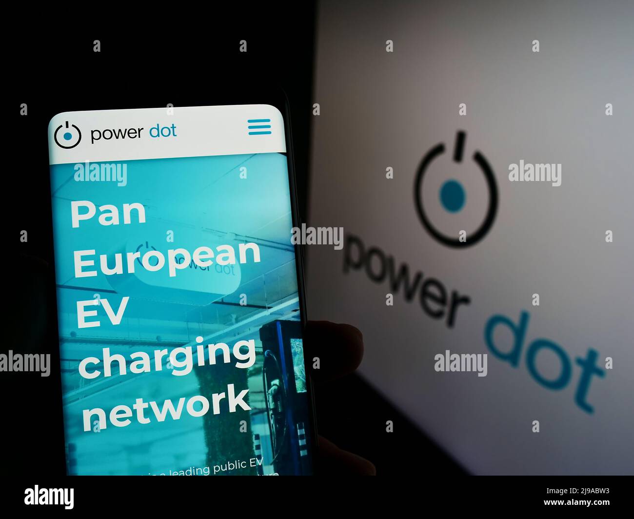 Person holding smartphone with website of Portuguese EV charging company Power Dot S.A. on screen with logo. Focus on center of phone display. Stock Photo