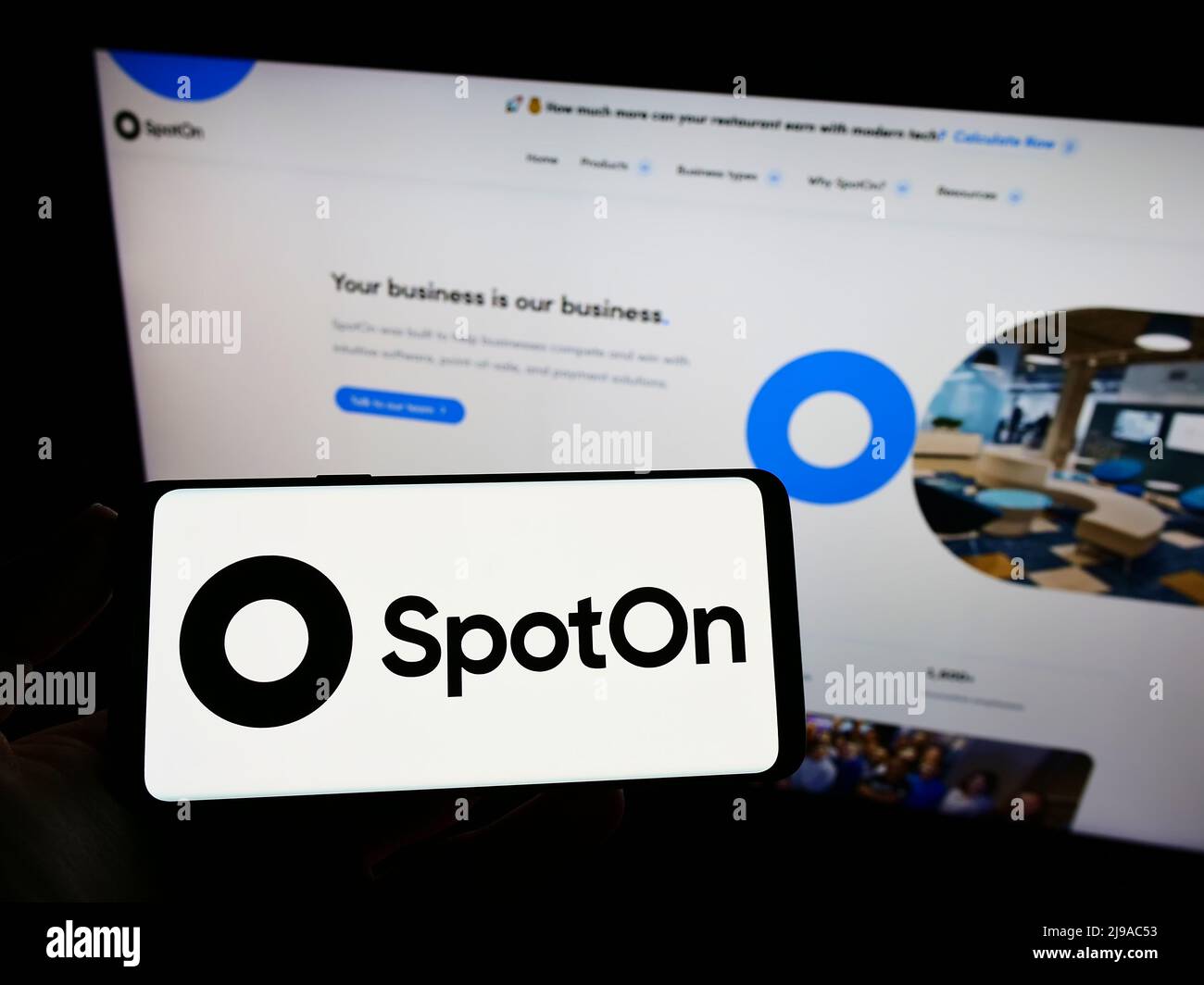 Person holding smartphone with logo of US software company SpotOn Transact LLC on screen in front of website. Focus on phone display. Stock Photo