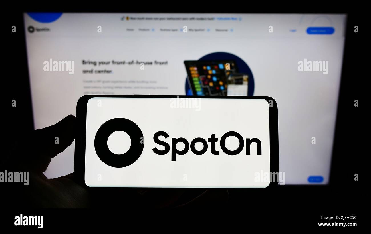 Person holding cellphone with logo of US software company SpotOn Transact LLC on screen in front of business webpage. Focus on phone display. Stock Photo