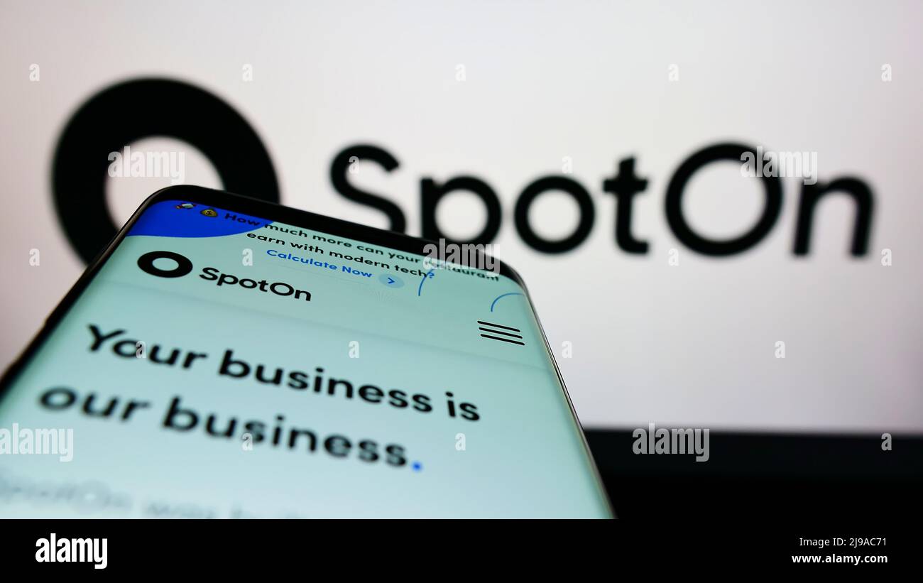 Mobile phone with webpage of US software company SpotOn Transact LLC on screen in front of business logo. Focus on top-left of phone display. Stock Photo