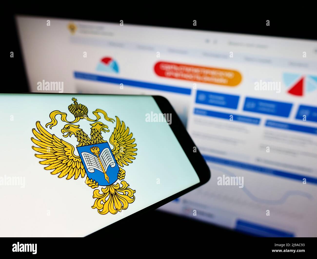 Mobile phone with logo of Russian Federal State Statistics Service (Rosstat) on screen in front of website. Focus on center of phone display. Stock Photo