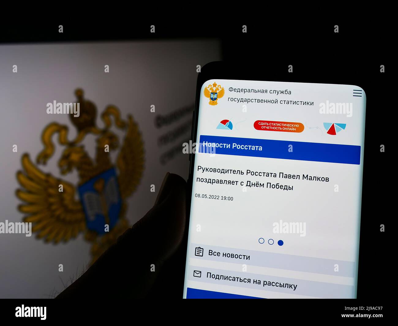 Person holding cellphone with website of Russian Federal State Statistics Service (Rosstat) on screen with logo. Focus on center of phone display. Stock Photo