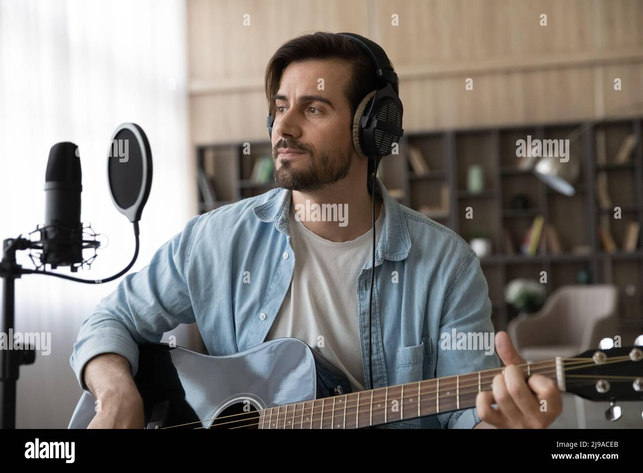 Inspired man singer in earphones hold guitar work on album Stock Photo