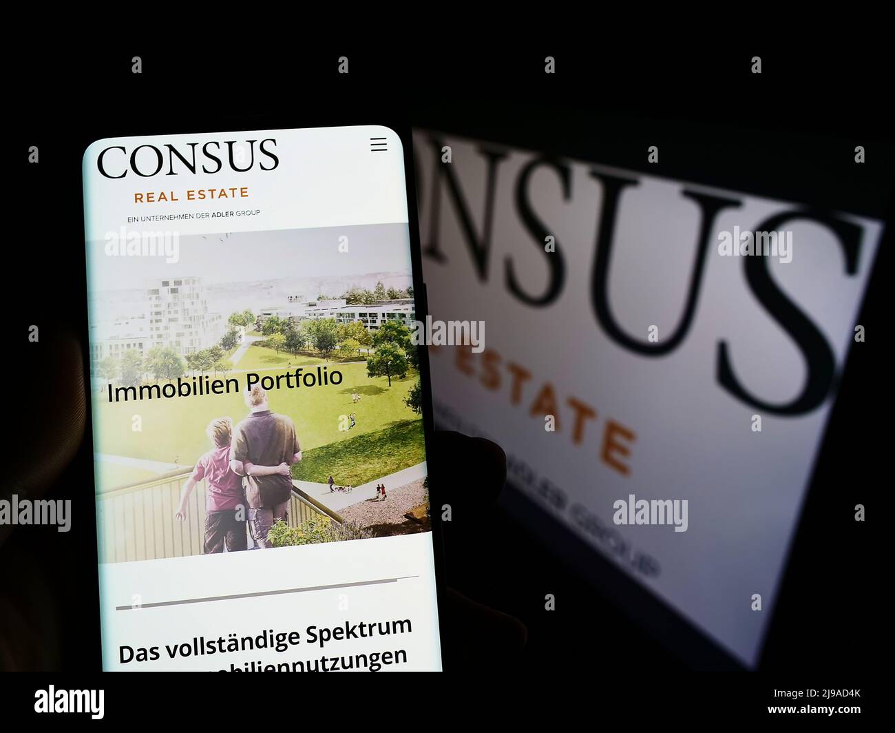 Person holding mobile phone with website of German company Consus Real