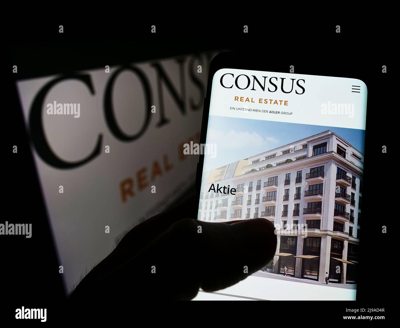 Person holding cellphone with webpage of German company Consus Real