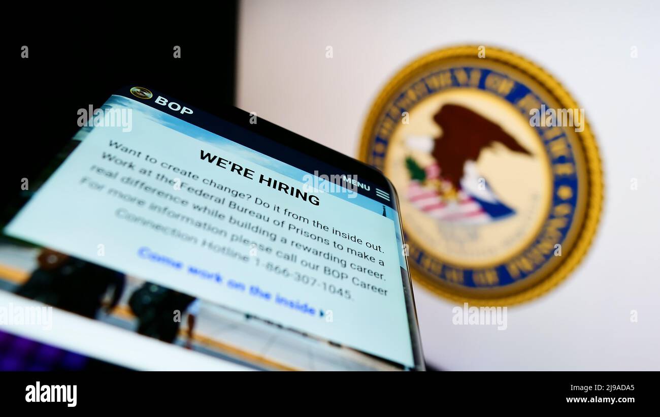 Mobile phone with website of US agency Federal Bureau of Prisons (BOP) on screen in front of logo. Focus on top-left of phone display. Stock Photo