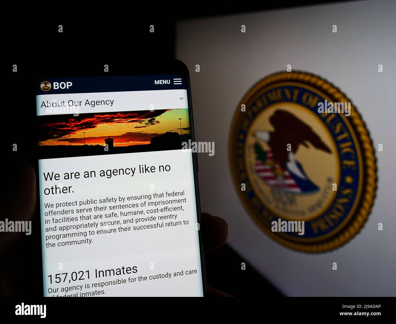 Person holding cellphone with webpage of US agency Federal Bureau of Prisons (BOP) on screen in front of seal. Focus on center of phone display. Stock Photo