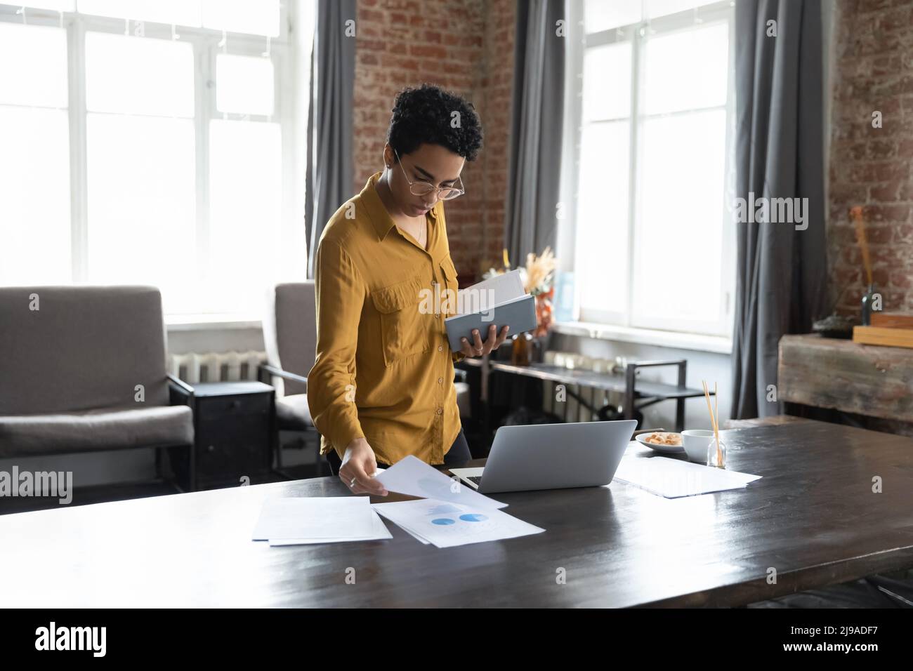 Serious African businesswoman sorting out papers working in modern office Stock Photo