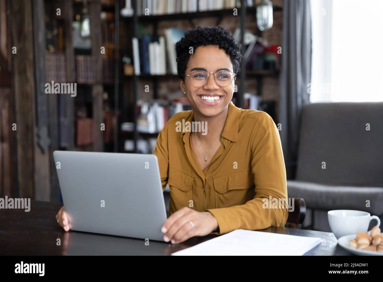 African woman distracted from working on laptop looks into distance Stock Photo