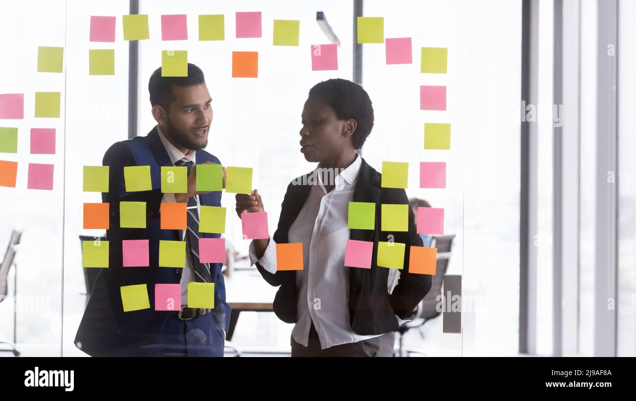 Millennial multiracial colleagues discuss creative ideas on sticky post-it notes Stock Photo