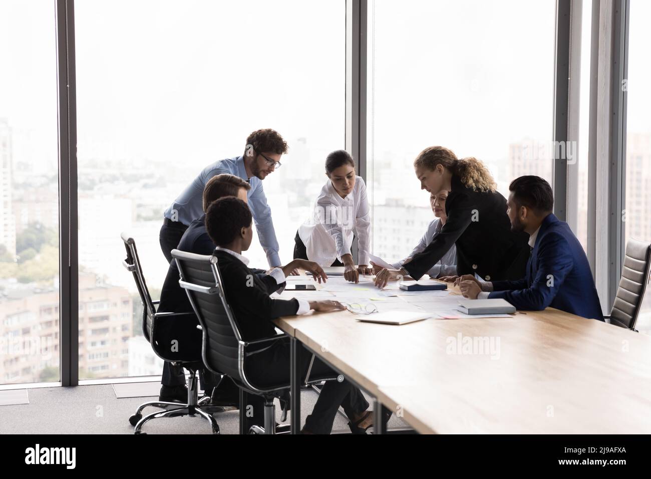 In modern boardroom diverse employees develop marketing strategy, analyze papers Stock Photo